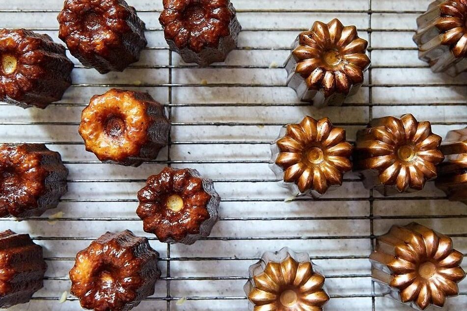 menggambarkan kue canele yang telah selesai dipanggang dan dikeluarkan dari cetakan tembaga